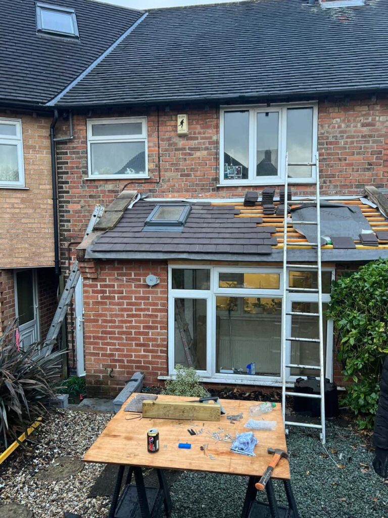 This is a photo of a roof extension that is having new roof tiles installed. This is a photo taken from the roof ridge looking down a tiled pitched roof on to a flat roof. Works carried out by Edenbridge Roofing Repairs