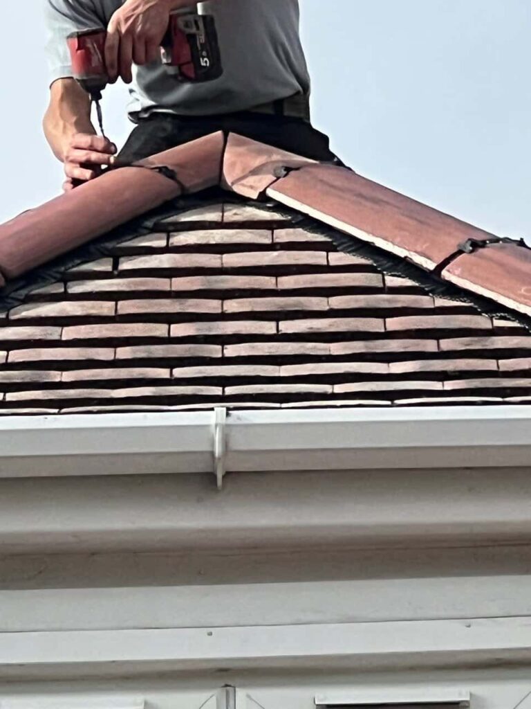 This is a photo of one of the operatives of Edenbridge Roofing Repairs installing new ridge tiles