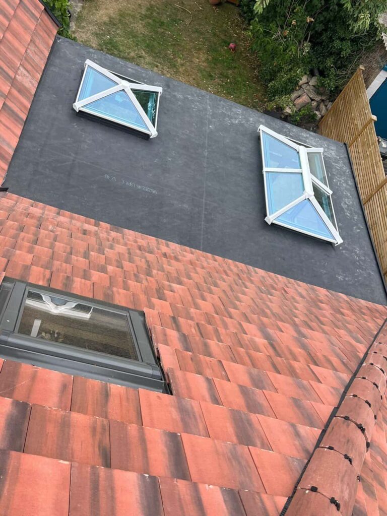 This is a photo taken from the roof ridge looking down a tiled pitched roof on to a flat roof. Works carried out by Edenbridge Roofing Repairs